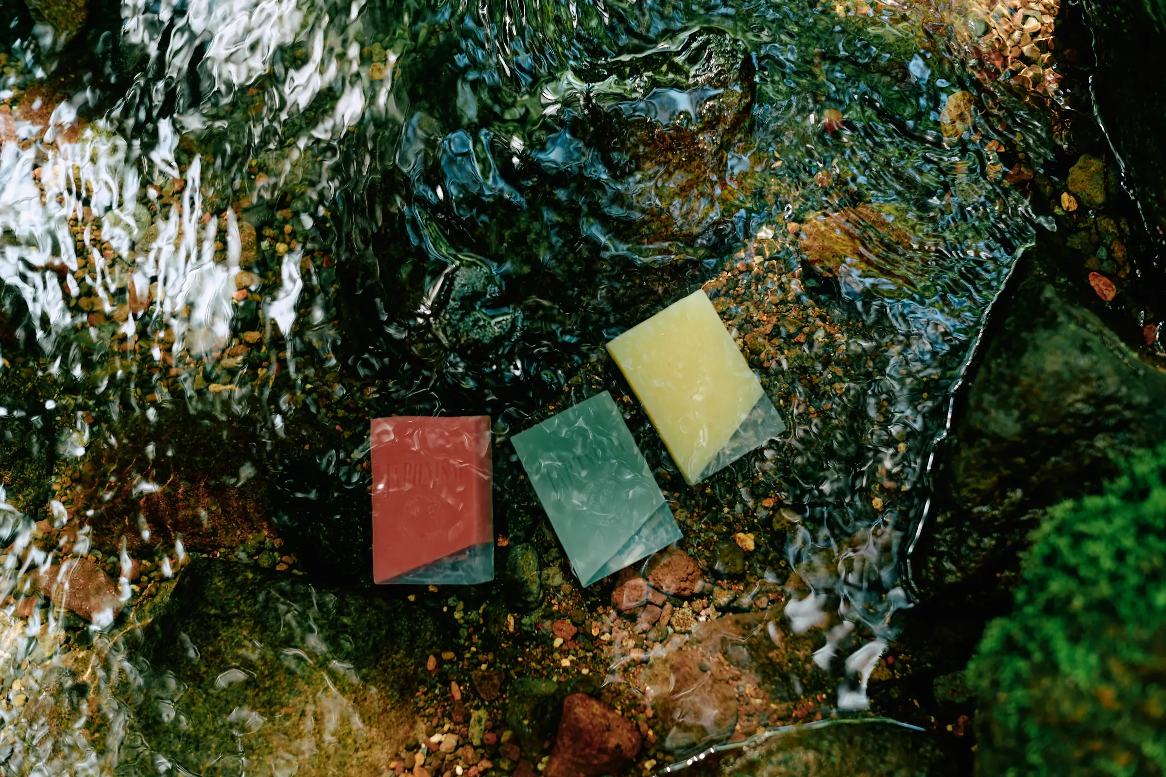 Unwrapped JAPONISM soap bars in a mountain stream